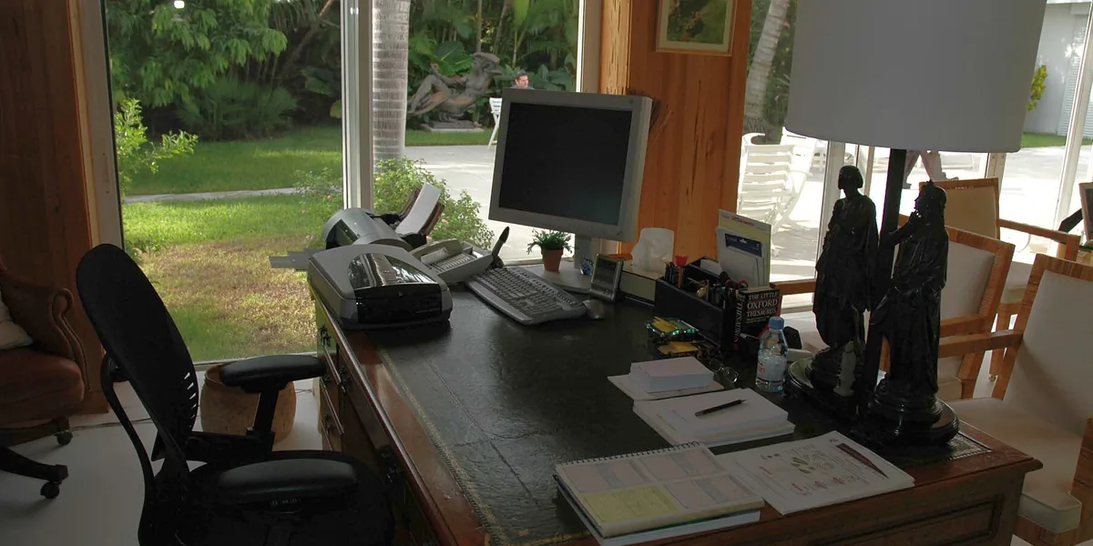 Schreibtisch mit Monitor, Lampe und Fenster