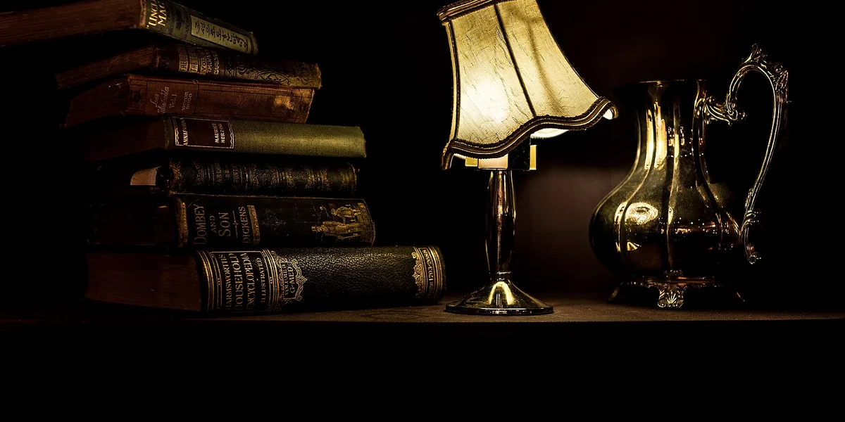 Lampe und Bücherstapel auf einem Bord